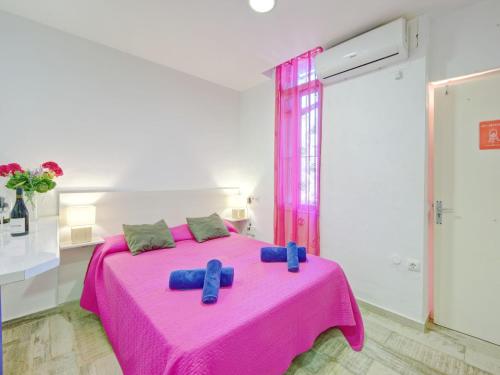 un letto rosa con cuscini blu in una stanza bianca di Studio Muralla Roja-3 by Interhome a Calpe