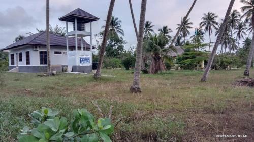 a small white building in a field with palm trees at Homestay Umar Homestay Tilam Hotel in Bachok