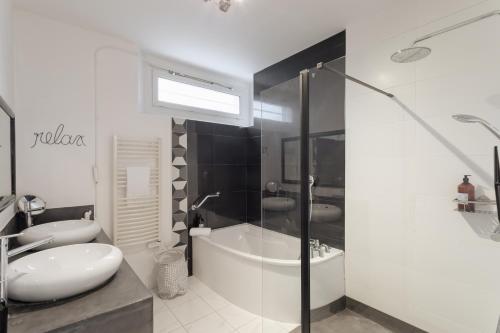 une salle de bain blanche avec une baignoire et un lavabo dans l'établissement Le Havane - Appt de 100m2 proche centre Rennes, à Rennes