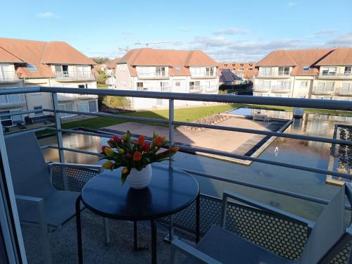 a balcony with a table with a vase of flowers on it at Studio Bowie with shared pool by Interhome in De Haan