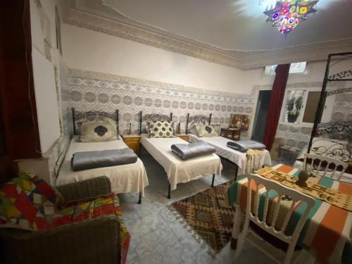 1 dormitorio con 2 camas y sofá en Riad Fez Hostel, en Fez