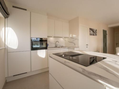 a kitchen with white cabinets and a black sink at Apartment Athene 002 with parking by Interhome in Bredene