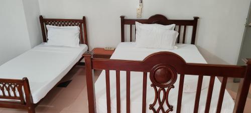 Duas camas num quarto com lençóis e almofadas brancos em Jays Guest, Diyatha Uyana em Etulkotte