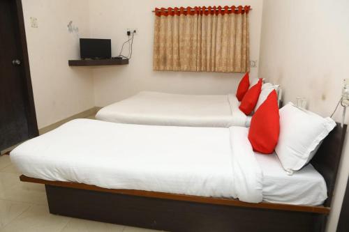 two beds with red pillows in a room at Hotel Shakti in Dwarka