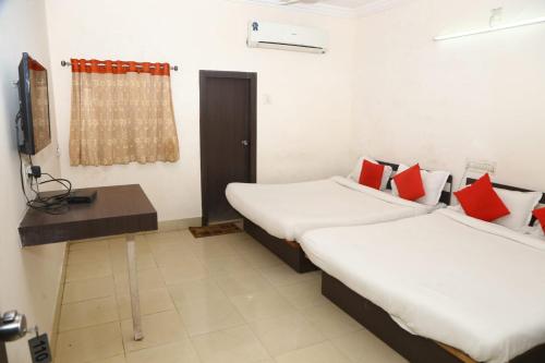 a room with two beds and a television in it at Hotel Shakti in Dwarka