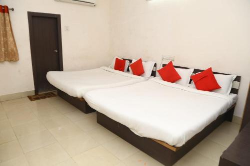 two beds in a room with red pillows at Hotel Shakti in Dwarka