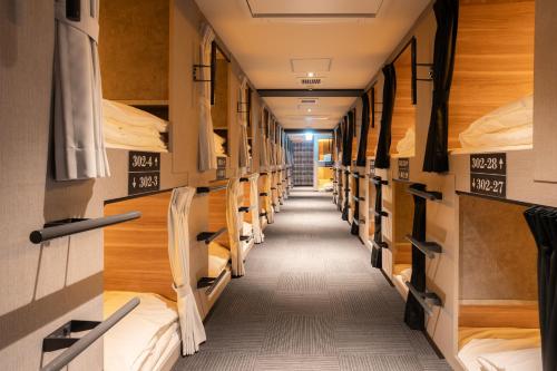 a long aisle of bunk beds in a dorm room at ピンポンホテル&キャビン pin pon hotel & cabin in Shunan