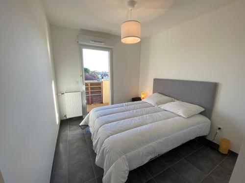 une chambre avec un grand lit blanc avec une fenêtre dans l'établissement AGATHE 3 pièces lumineux centre ville, à La Teste-de-Buch