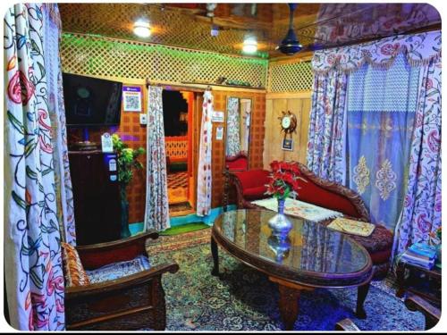 King of kings Houseboat في سريناغار: غرفة معيشة مع طاولة وكراسي زجاجية