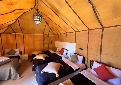 a group of beds in a room with wooden walls at Camel trekkings in Adrouine