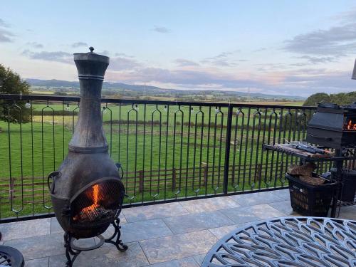 a fire pit on a balcony with a table and a view at Burtree Country House and Retreat in Thirsk