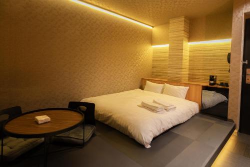 Cette petite chambre comprend un lit et une table. dans l'établissement ピンポンホテル&キャビン pin pon hotel & cabin, à Shunan