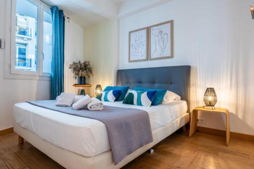 a bedroom with a large bed with blue accents at SERRENDY Apartment with terrace & sea view in Cannes