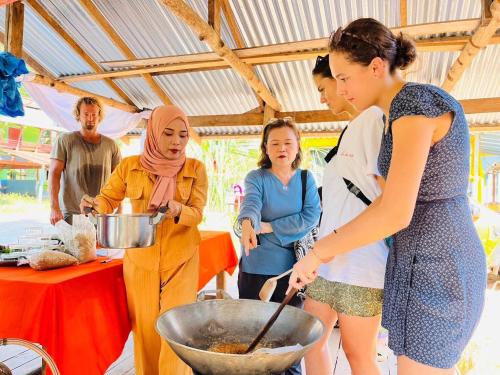 a group of people standing around a bowl of food at Banhalawee in Ko Yao Yai