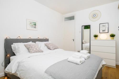 a bedroom with a large white bed with towels on it at Lovely Apartment in Victoria Park Village in London