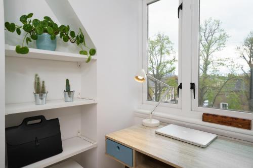 einen Schreibtisch mit einem Laptop und einem Fenster in der Unterkunft Lovely Apartment in Victoria Park Village in London
