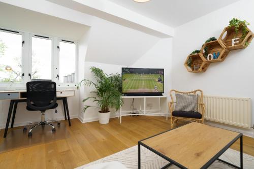 an office with a desk and a tv in a room at Lovely Apartment in Victoria Park Village in London