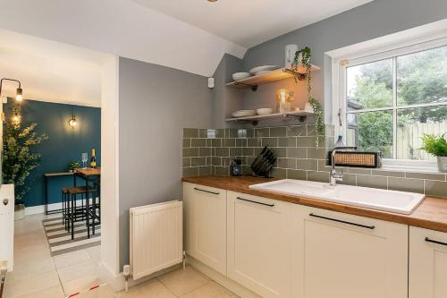 eine Küche mit weißen Schränken, einem Waschbecken und einem Fenster in der Unterkunft Stunning 3BD Oxfordshire Cottage in Enstone in Enstone