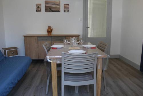 einen Esstisch mit Stühlen und einen Tisch mit Weingläsern in der Unterkunft Ronce-les-Bains - APPARTEMENT REZ-DE-CHAUSSÉE droit - 90m de la PLAGE in Ronce-les-Bains