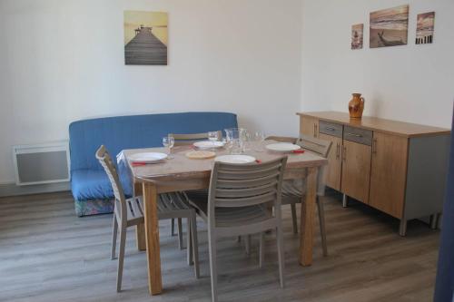 une table à manger avec des chaises et un canapé bleu dans l'établissement Ronce-les-Bains - APPARTEMENT REZ-DE-CHAUSSÉE droit - 90m de la PLAGE, à Ronce-les-Bains