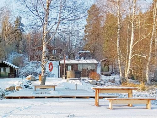 dois bancos na neve em frente a uma cabine em Holiday Home Hiidenlumo by Interhome em Vihti