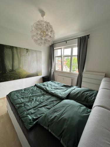 um quarto com uma cama verde e um lustre em Ferienwohnung Eisenach Süd em Eisenach