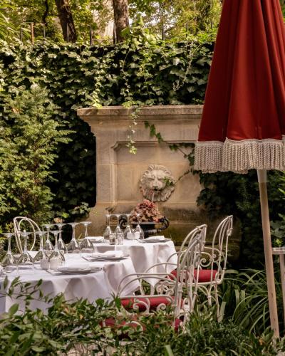 une table avec des verres à vin et un parasol rouge dans l'établissement Hôtel Particulier Montmartre, à Paris