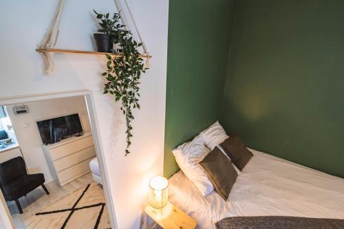 - une chambre avec un lit et une plante sur le mur dans l'établissement Bali - Studio agréable et central - Proche Arena, à Reims