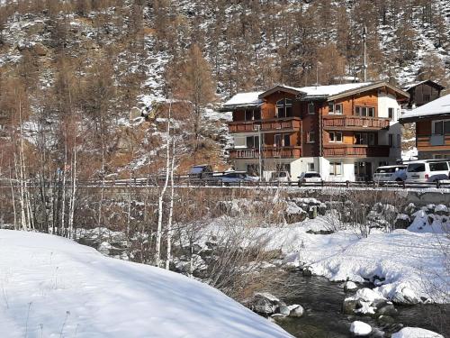 une maison dans la neige à côté d'une rivière dans l'établissement Apartment Alpin Smile by Interhome, à Saas-Almagell