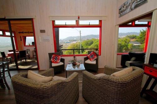 a living room with chairs and a table and windows at Cabaña con tinaja a pasos de la playa in Boca Pupuya