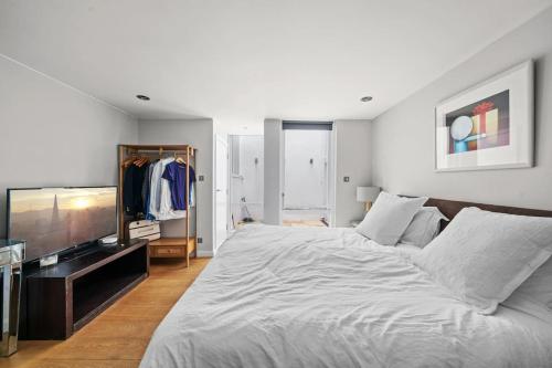 1 dormitorio con 1 cama grande y TV en Lovely Mews House Royal Crescent en Londres