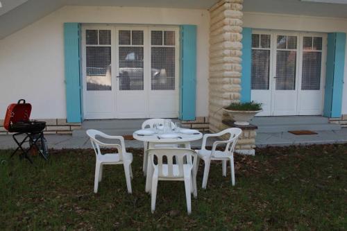 une table et des chaises blanches devant une maison dans l'établissement Ronce-les-Bains - APPARTEMENT REZ-DE-CHAUSSEE gauche - 90m de la PLAGE, à Ronce-les-Bains