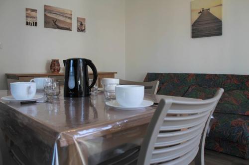 une table en bois avec des tasses et des assiettes blanches dans l'établissement Ronce-les-Bains - APPARTEMENT REZ-DE-CHAUSSEE gauche - 90m de la PLAGE, à Ronce-les-Bains