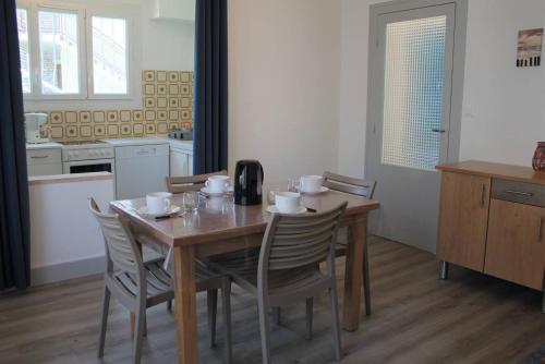 eine Küche mit einem Holztisch mit Stühlen und einem Esszimmer in der Unterkunft Ronce-les-Bains - APPARTEMENT REZ-DE-CHAUSSEE gauche - 90m de la PLAGE in Ronce-les-Bains