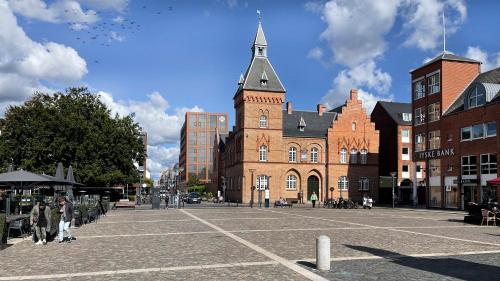 a city street with a large brick building with a tower at Cabinn Plus Esbjerg in Esbjerg
