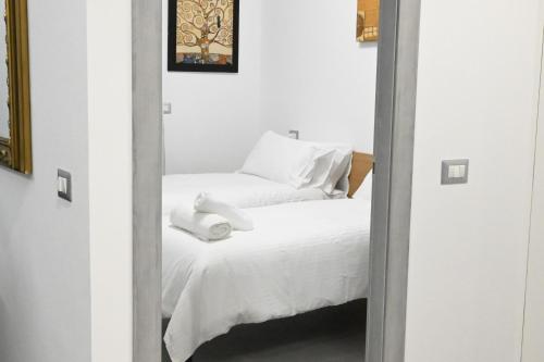 een spiegel die een bed reflecteert met witte lakens en handdoeken bij Casa karas in Milaan