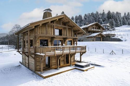 una cabaña de madera en la nieve cubierta de nieve en Chalet Mayen, luxueux et intimiste, en Ban-sur-Meurthe-Clefcy