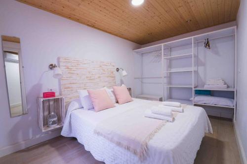 ein Schlafzimmer mit einem großen weißen Bett mit rosa Kissen in der Unterkunft Apartamento en la mejor zona de Triana, junto al puente in Sevilla