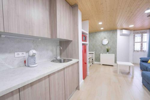 eine Küche mit einem Waschbecken und ein Wohnzimmer in der Unterkunft Apartamento en la mejor zona de Triana, junto al puente in Sevilla