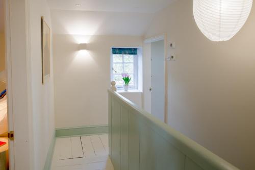 a white hallway with a staircase with a window at The Villa in Coberley - Stylish 3BD with Garden! 
