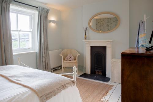 a bedroom with a bed and a mirror and a fireplace at The Villa in Coberley - Stylish 3BD with Garden! 