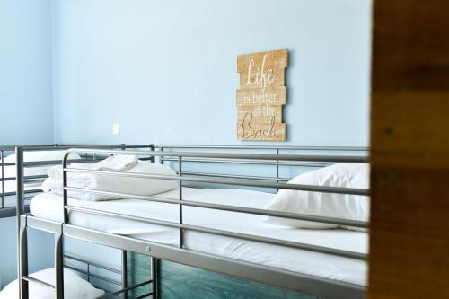 a bedroom with two bunk beds with white sheets at Single Fin Hotel & Lodge in Mimizan-Plage