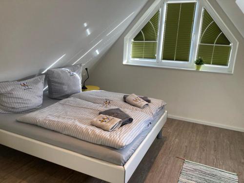 a bed with two pillows on it in a room at Bootshaus SunDeck - Strandnah in den Dünen in Wangerooge