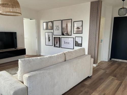 a living room with a white couch and pictures on the wall at Appartement cosy au cœur de la ville in Aurillac