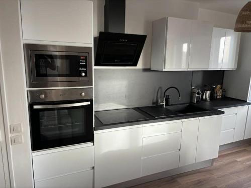 a kitchen with white cabinets and stainless steel appliances at Appartement cosy au cœur de la ville in Aurillac