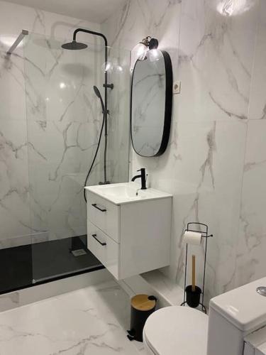 a white bathroom with a sink and a mirror at Appartement cosy au cœur de la ville in Aurillac