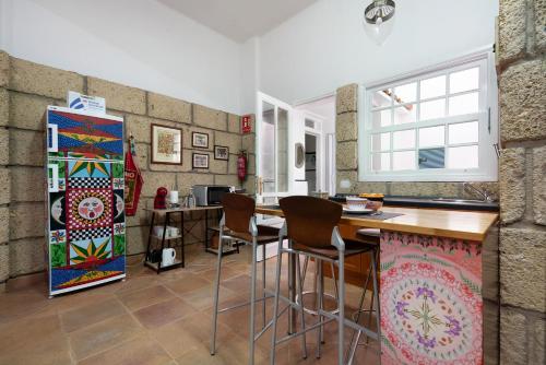 a kitchen with a counter with chairs and a refrigerator at Loft Parque Santa Cruz in Santa Cruz de Tenerife
