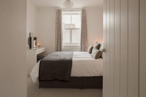 a white bedroom with a bed and a window at Stunning 2 Bed with Private Patio and Free Parking in Cheltenham