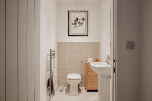 a white bathroom with a toilet and a sink at Stunning 2 Bed with Private Patio and Free Parking in Cheltenham