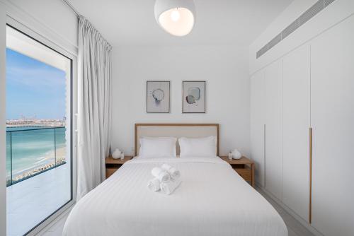 a bedroom with a white bed and a large window at 3Bed Private Beach - Belle vie à La Vie Dubai in Dubai